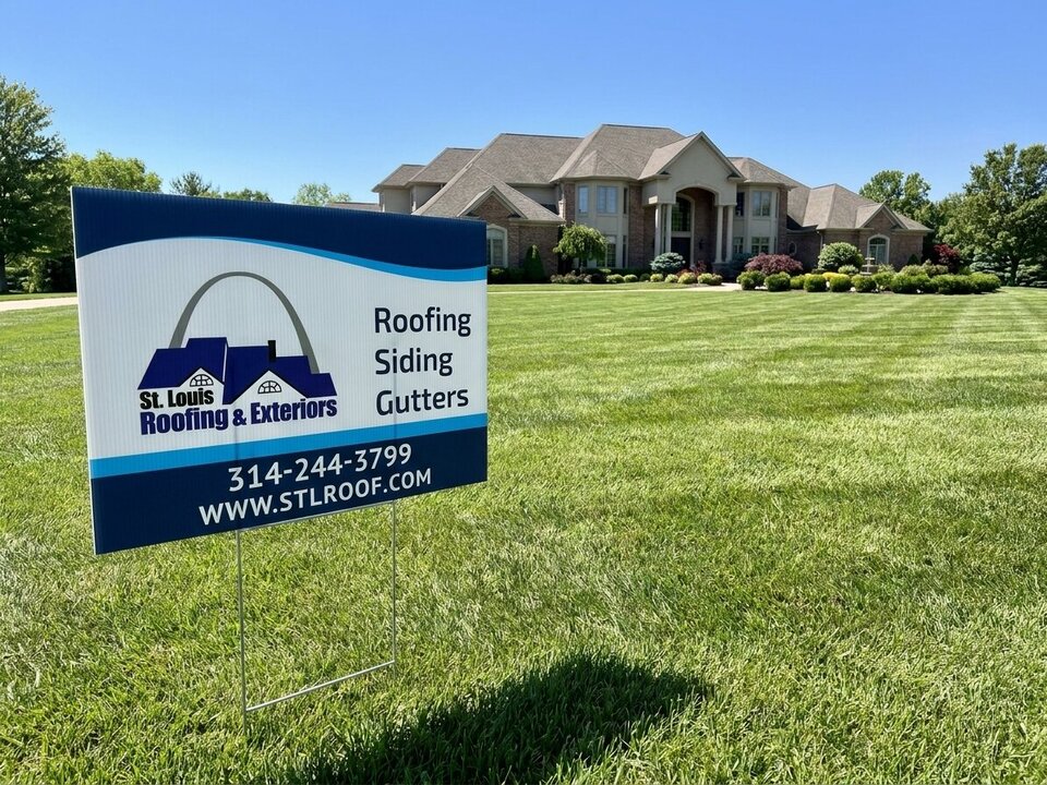 A large brick house with a St. Louis Roofing & Exteriors yard sign on the lawn.