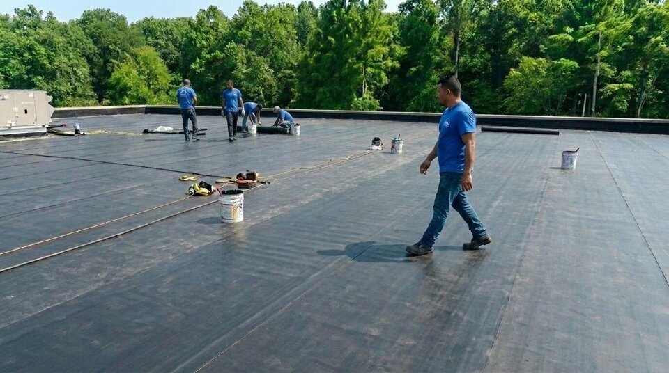 A crew welding membrane on a commercial flat roof.