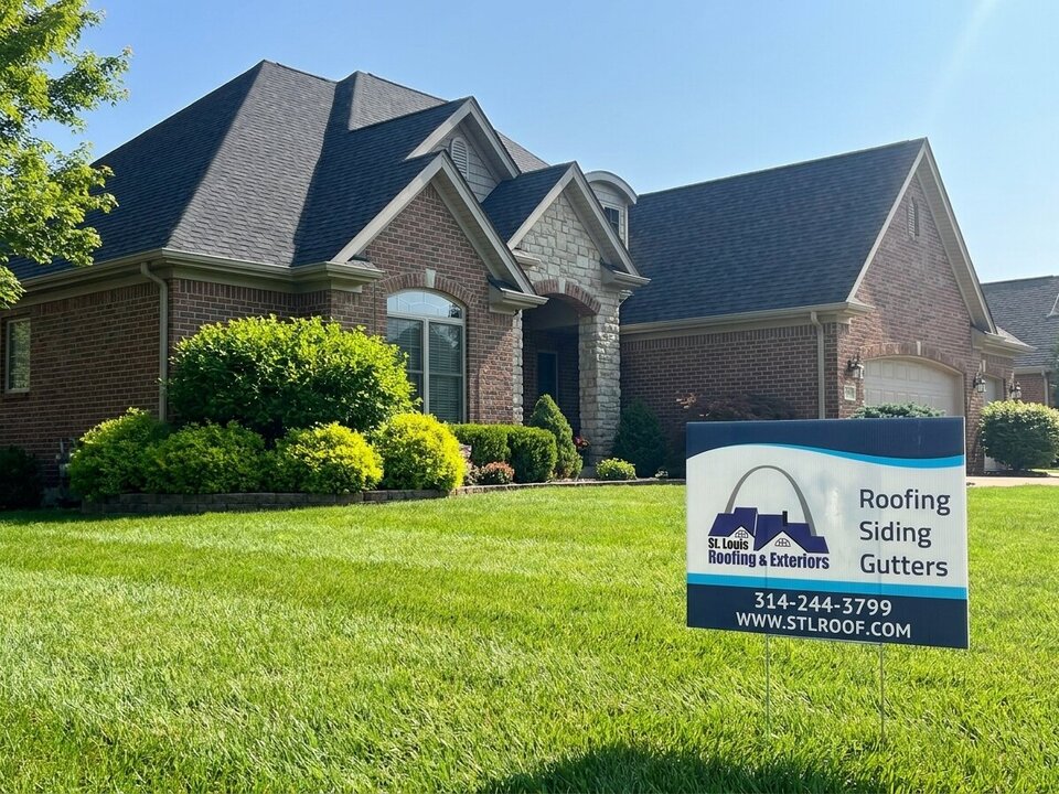 A completed shingle roof over a brick and stone house.