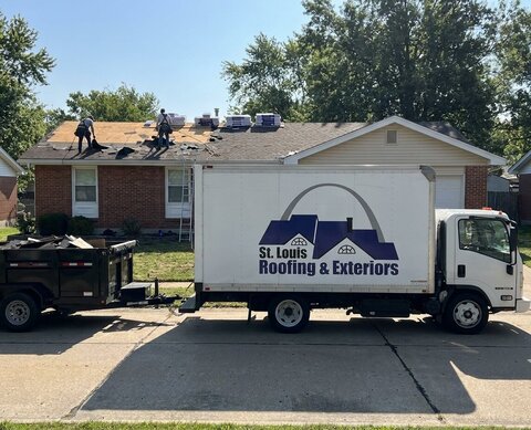 A crew and truck at a house mid tear-off.